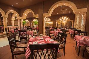 Restaurant im Sunrise Royal Makadi Resort mit roten und weißen Tischdecken.