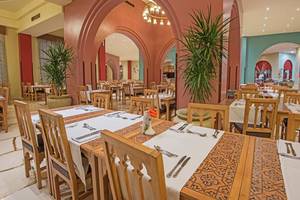 Innenansicht des Restaurants im Sunrise Royal Makadi Resort mit gedeckten Tischen und Stühlen.