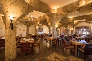 Das geräumige Restaurant im Sunrise Royal Makadi Resort mit steinernen Säulen und Holztischen.