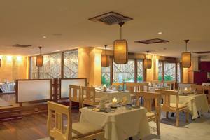 Innenansicht des Restaurants im Diani Reef Beach Resort & Spa mit Tisch, Stühlen, Kerzen und Lampen.