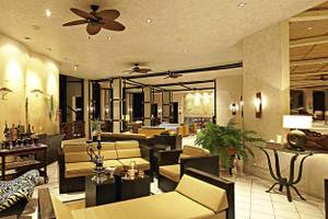 Loungebereich des Diani Reef Beach Resort & Spa mit afrikanischem Dekor, Deckenventilatoren und Möbeln.