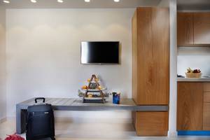 Wohnzimmer von Anna's House mit Fernseher an der Wand, Tisch mit Früchten und Tasche.