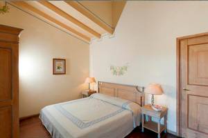 Schlafzimmer im Bagaglino I Giardini di Porto Cervo Hotel mit Bett, Nachttischen und Lampen.