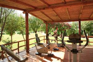 Fitnessbereich im Freien im Hotel Giardini di Porto Cervo mit Geräten und einem Mann, der läuft.