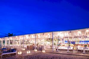 Nachtansicht des Mykonos Ammos Hotel-Strand-Lounge-Bereichs mit weißen Möbeln und Beleuchtung.