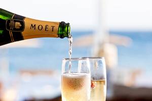 Moët Champagne wird in zwei Gläser gegossen, am Strand.