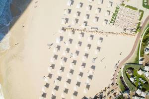 Luftaufnahme des Jumeirah Mina A'Salam Strandes mit vielen weißen Sonnenschirmen und Gästen.