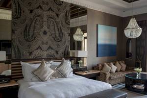 Innenansicht eines Schlafzimmers im Jumeirah Mina A'Salam Hotel mit Bett, Lampen und Dekor.