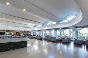 Lobby im Apollo Beach Hotel mit modernen Möbeln, hohen Decken und großen Fenstern.