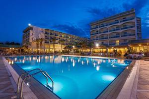 Außenpool des Apollo Beach Hotels bei Nacht mit Gästebereich und Beleuchtung.