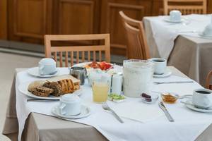 Frühstückstisch im Apollo Beach Hotel mit Brot, Marmelade, Kaffee und Fruchtsaft.
