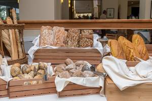 Brotbuffet im Apollo Beach Hotel mit verschiedenen Brotsorten in Holzkörben auf einem Tisch.