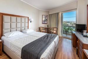 Doppelzimmer im Apollo Beach Hotel mit zwei Betten, Nachttischen und einer Aussicht auf die Stadt.