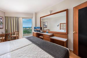 Doppelzimmer mit Meerblick im Apollo Beach Hotel, mit zwei Betten, Schreibtisch und Aussichtsfenster.