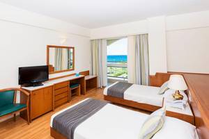 Doppelzimmer mit Meerblick im Apollo Beach Hotel mit zwei Betten, Fernseher, Schreibtisch und Balkon.