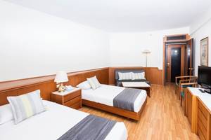 Doppelzimmer im Apollo Beach Hotel mit zwei Betten, Fernseher, Lampe und Couch