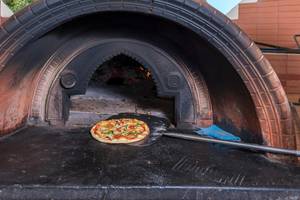 Eine Pizza wird in einem Holzofen des Apollo Beach Hotels gebacken.