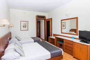 Doppelzimmer im Apollo Beach Hotel mit zwei Betten, Dekor, Spiegel und Fernseher.