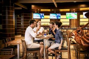 Gruppe von Gästen, die in einem Barbereich des Barcelo Maya Grand Resort Hotels sitzen und essen.
