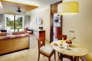 Wohnbereich des Barcelo Maya Grand Resort mit Couch, Tisch, Lampe und Fernseher.