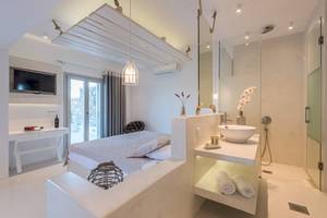 Suite im Sunrise Mykonos Hotel mit Bett, Fernseher und Dusche.