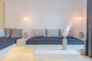 Suite im Sunrise Mykonos Hotel mit weißen Möbeln, blauen Kissen und Orchideen-Vase auf Tisch
