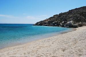 Strand mit felsigem Ufer und blauem Wasser unter einem blauen Himmel