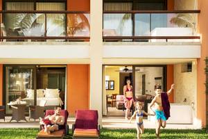 Familie genießt den Außenbereich des Barcelo Maya Grand Resort mit Balkon, Liegestühlen und Spielplatz