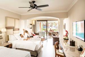 Suite im Barcelo Maya Grand Resort mit zwei Betten, Wohnzimmer und Terrasse.