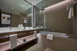 Modernes Badezimmer im Mysk Al Mouj Hotel mit Doppelwaschbecken, Badewanne und Dusche.
