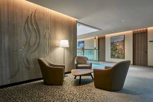 Lobby-Lounge-Bereich im Mysk Al Mouj Hotel mit Möbeln, Lampen und Kunstwerken.