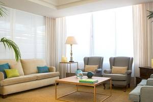 Wohnzimmer im Universal Hotel Neptuno mit Sofa, Sesseln, Tisch und Lampe.