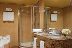 Badezimmer im Universal Hotel Neptuno mit Badewanne, Glasdusche und Waschbecken.