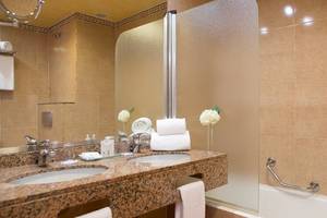 Badezimmer im Universal Hotel Neptuno mit zwei Waschbecken, Spiegel, Badewanne und Handtüchern.