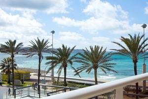 Aussicht von Universal Hotel Neptuno auf eine Palmenallee und den Strand.
