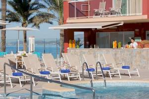 Poolbereich des Universal Hotel Neptuno mit Bar und Liegestühlen am Meer.