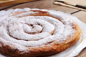 Ein Spiralgeburtstagskuchen mit Puderzucker bestreut auf einem weißen Teller.