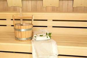 Holzsauna mit einem Holzeimer und Handtüchern auf der Bank.