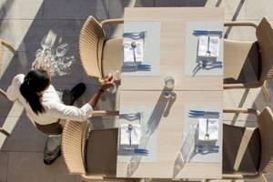 Ein Kellner bereitet einen Tisch im Freien im Universal Hotel Neptuno vor.