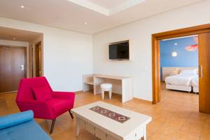 Innenansicht eines Zimmers im Iberostar Founty Beach Hotel mit Wohnzimmer, Fernseher und Schlafzimmer.