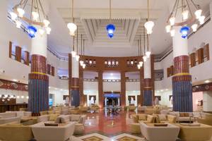 Lobby des Iberostar Founty Beach Hotels mit blauen Kronleuchtern, runden Tischen und Sofas.