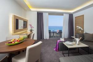 Hotelzimmer mit Meerblick im Royal Apollonia Beach Hotel mit Balkon, Tisch, Stühlen und Aussicht auf das Meer.