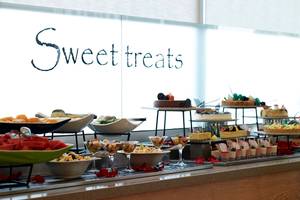 Buffet mit süßen Häppchen im Royal Apollonia Beach Hotel, darunter Kuchen, Obst und Desserts.