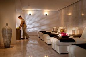 Spa-Lounge im Royal Apollonia Beach Hotel mit weißen Möbeln und hellem Licht.