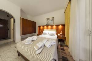 Ein Schlafzimmer im Zante Palace Hotel mit einem Doppelbett, weichen Bettdecken, und hölzerne Nachttische.