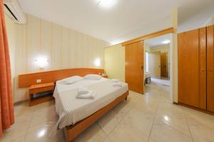 Schlafzimmer im Zante Palace Hotel mit Doppelbett, Nachttischen und Kleiderschränken.