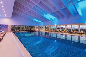 Innenpool des Hotels Dubrovnik President Valamar Collection mit Loungestühlen und blauer Beleuchtung.