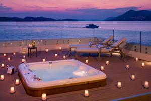 Terrasse mit Whirlpool und Kerzen bei Abendstimmung mit Blick aufs Meer