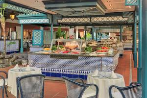 Innenansicht des Restaurants Seaside Los Jameos mit blau-weiß gefliester Theke, Tischen und Stühlen.