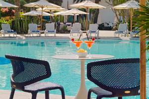 Cocktails am Pool des Seaside Los Jameos Hotels mit Sonnenschirmen und Stühlen im Hintergrund.